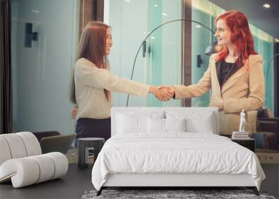 Western business women shaking hands in a meeting room, Multi ethnic Wall mural