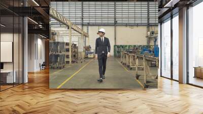 Western businessman, caucasian, an engineer or worker walking in manufacturing factory with equipment machine engine production system work, technology in operation in industry plant in warehouse. Wall mural