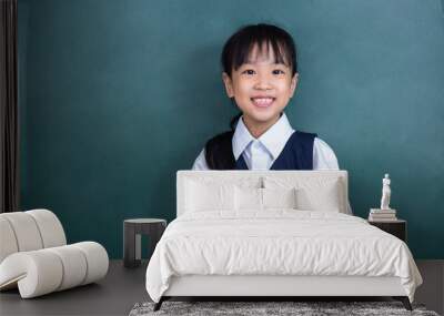 Asian Chinese little Girl in uniform reading book against green blackboard Wall mural