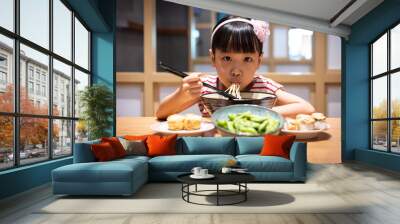 Asian little Chinese girl eating ramen noodles Wall mural