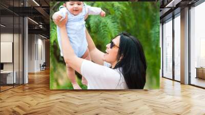 young mother playing with her baby  in the garden Wall mural