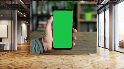 Hand Holding Smartphone with Green Screen Display on Wooden Table Wall mural