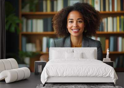 A woman with curly hair is sitting in a chair in front of a bookshelf Wall mural