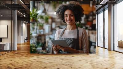 A woman with curly hair is smiling and holding a tablet in a flower shop Wall mural