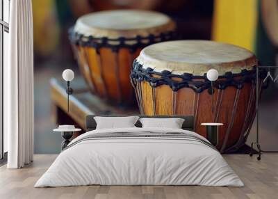 Two traditional drums sit on a wooden stand, showcasing their natural wood grain and intricate stitching. Wall mural