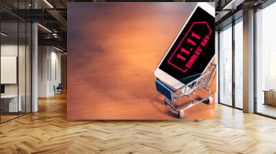 Smartphone with 11.11 message on screen inside a small shopping cart, singles day online shopping concept Wall mural