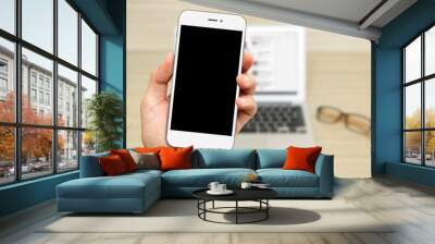 Hand Hold white Smartphone with laptop background Wall mural