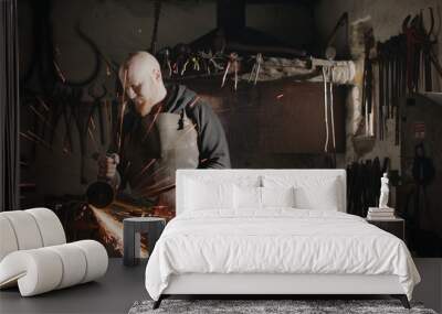 Young blacksmith with angle grinder in his workshop Wall mural