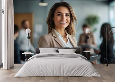 Businesswoman leader holding a tablet in her hand and standing in an office at team meeting. Wall mural