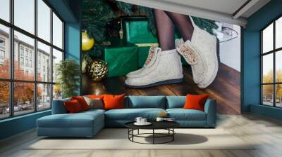 gray felt boots on the legs against the background of the Christmas tree. Wall mural