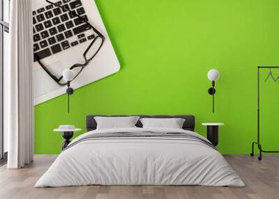 top view of white laptop with glasses on isolated green Wall mural