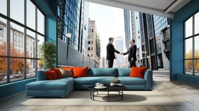 two businessmen shaking hands on background office buildings Wall mural