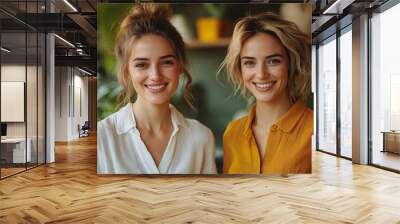 Two smiling women, side by side, in a plant-filled room. Their relaxed, happy expressions suggest friendship or professional success in a bright, welcoming space Wall mural