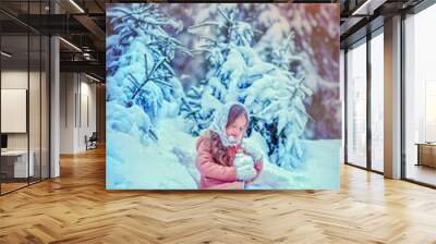 Beautiful little girl with long hair. Little girl in the winter forest. girl in a white knitted scarf. Girl in a Zara sheepskin coat. The little girl looks up to the sky. The little girl smiles.  Wall mural