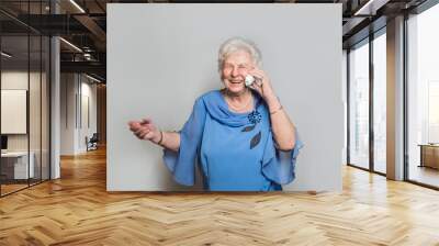 Seniorin lacht herzlich am Telefon. Sie trägt eine schicke blaue Bluse. Textfreiraum Wall mural