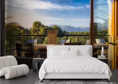 A few chairs and tables on a mediterranean style balcony with a marvellous view over beautiful summer landscape and mountains in the background Wall mural