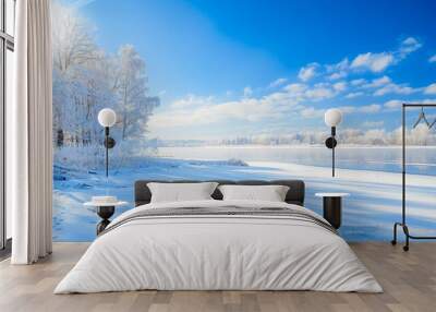 A serene winter landscape with a frozen lake and snow-covered trees under a bright blue sky Wall mural