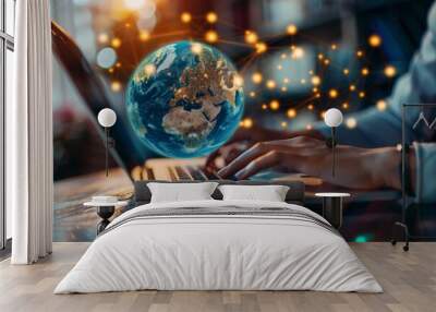 A person sits at a desk, focused on typing on a laptop while a glowing globe with illuminated connections hovers above, signifying global communication and technology advancement. Wall mural