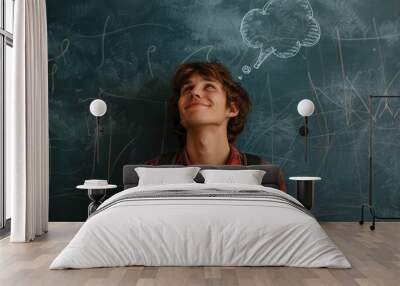 A young male student with a backpack looks up, smiling as he contemplates thoughts represented by a thought bubble on a chalkboard in a classroom. Wall mural