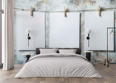 Three blank white sheets hang on a line with clothespins, set against a textured wall. Wall mural