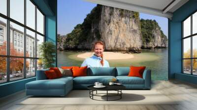 Young white red-haired woman in a blue fleece jacket stands against the background of rocks in Halong Bay, Vietnam Wall mural