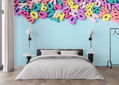 Lots of scattered multicolored letters on blue background . Learning to read, alphabet. Wall mural