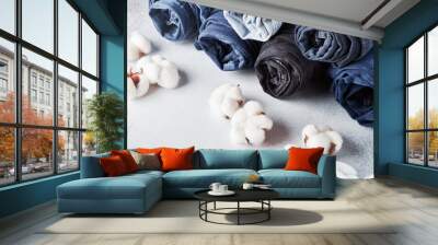 Rolled jeans and cotton flowers on light background Wall mural