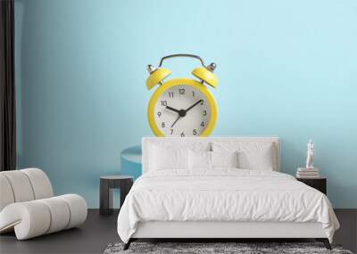 yellow alarm clock on a podium on a blue background. Wall mural