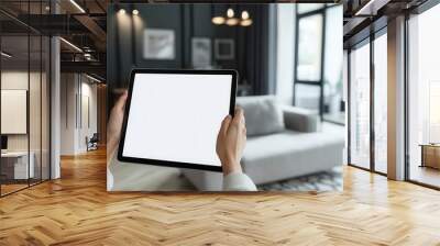 A person holds a blank tablet screen in a modern living room, showcasing a stylish interior design. Wall mural