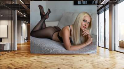 Beautiful blonde girl with perfect legs and butt posing on the sofa in a luxury lace bra and black pantyhose. Beauty glamour photo. Wall mural