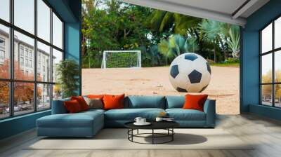 Soccer ball on the sand beach with small goal in the background Wall mural