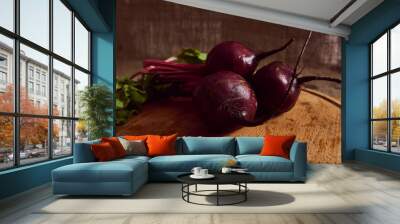 Bunch of fresh burgundy wet beetroot with green tops and leaves on a wooden cutting board . Food background of seasonal raw vegetables. Close-up Wall mural