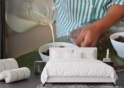 Pouring milk into a bowl of chocolate cereal for a morning breakfast routine Wall mural