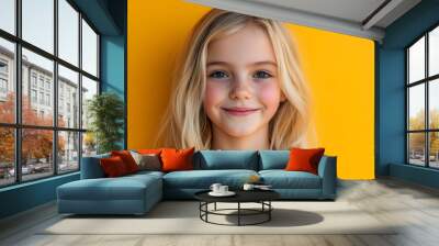 A young girl smiles brightly against a vibrant yellow wall, showcasing joy and confidence Wall mural