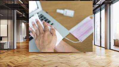 Close up image of businessman use wet wipes after touching objects and computer laptop in the pubic office with face mask and spray alcohol on wooden table To protect against corona viruses. Wall mural