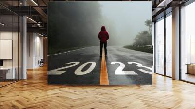 Man standing alone on the road and looking at target with text 2023 written on the road in the middle of asphalt road with at sunset. Concept of planning, goal, challenge, new year resolution.. Wall mural