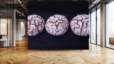 Chocolate cookies with cracks, strewed with icing sugar. Homemade baking, dark background. Selective focus, close-up. Wall mural