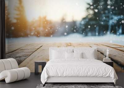 A rustic wooden table sits empty in a snowy winter setting, with soft snowfall and warm sunlight illuminating the peaceful scenery Wall mural