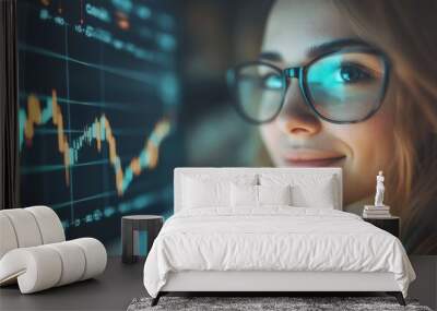 A smiling young woman confidently examines financial stock market data on a digital screen in a contemporary office setting Wall mural