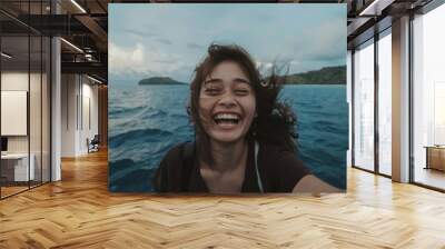 An exuberant woman with a joyful smile feeling the sea breeze on a boat trip. Wall mural