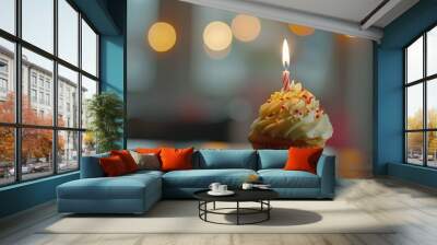 Close-up of a cupcake with a lit candle, surrounded by a warm bokeh background, perfect for celebrations. Wall mural