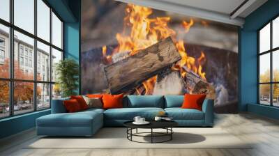 Crackling wood fire burning in a metal fire pit, capturing the warmth and ambiance of a campfire. Wall mural