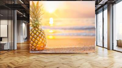 Golden pineapple on a sandy beach with ocean waves and a beautiful sunset in the background. Wall mural