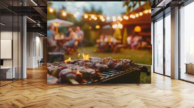 Grilled meats on a barbecue with a blurred background of people enjoying a summer evening outdoor party with festive lights. Wall mural