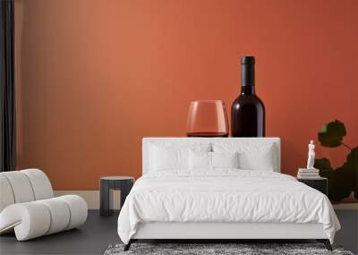 Red wine bottle with a glass on a simple orange empty background Wall mural