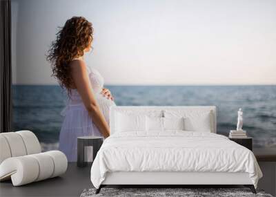 Young pregnant woman walking on the beach  Wall mural