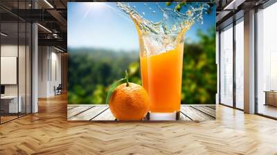 orange with water splash and a juice glass aside on a wooden table & a nature background Wall mural