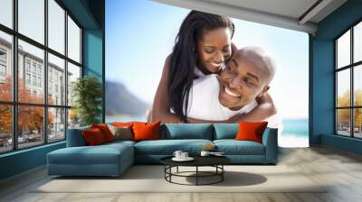 Surprise, my love. A handsome african-american man giving his girlfriend a piggyback on the beach. Wall mural