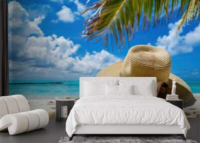 Straw hat and sunglasses on a sandy beach with blue ocean and palm leaves. Summer vacation and tropical travel concept. Wall mural