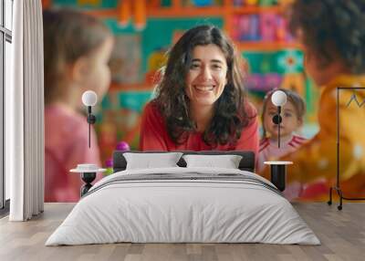 A woman is smiling at a group of children playing with blocks Wall mural